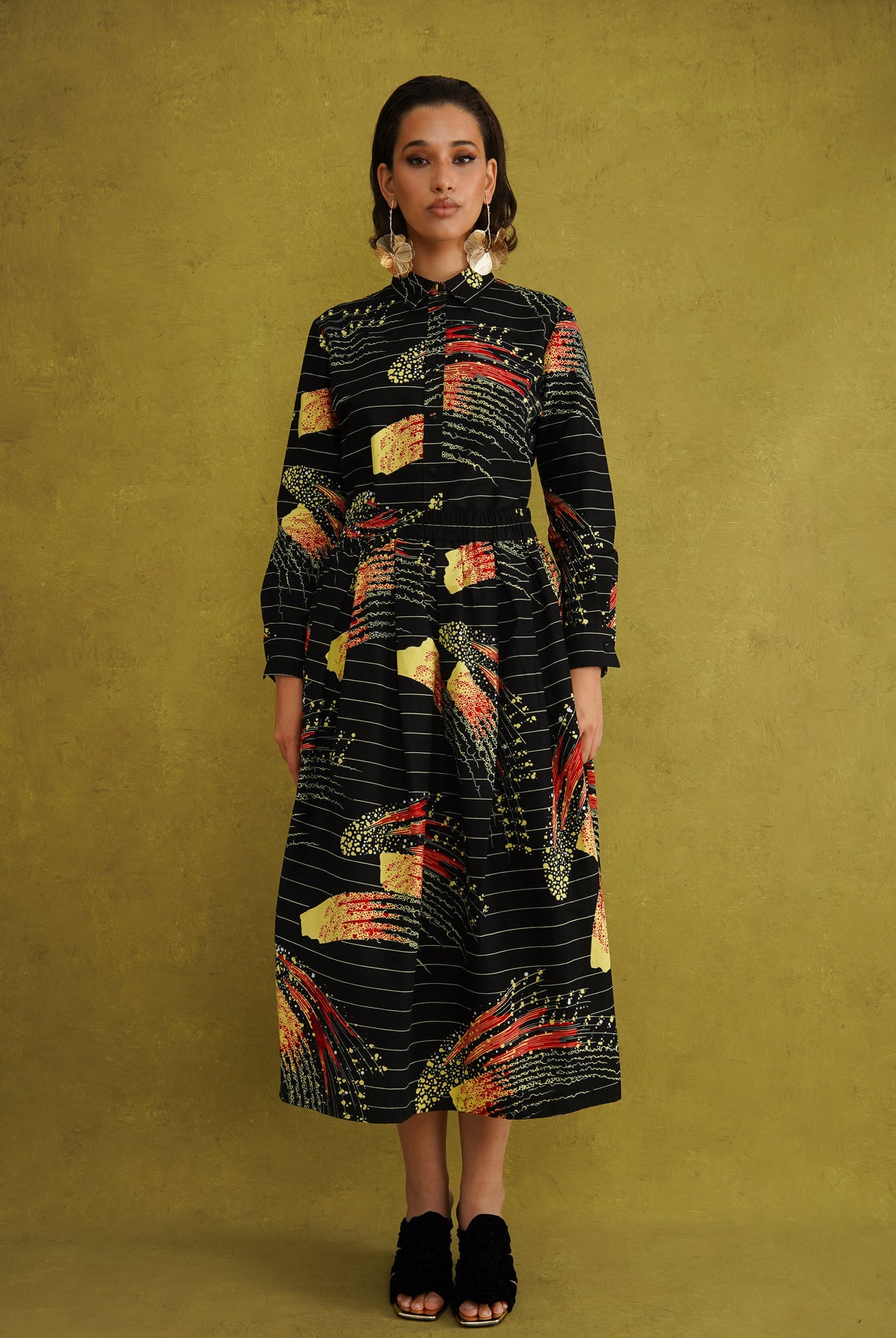 Ariya Cotton Midi Skirt, a tulip-shaped midi skirt in red and yellow Fireworks print Dutch wax cotton on a blue background
