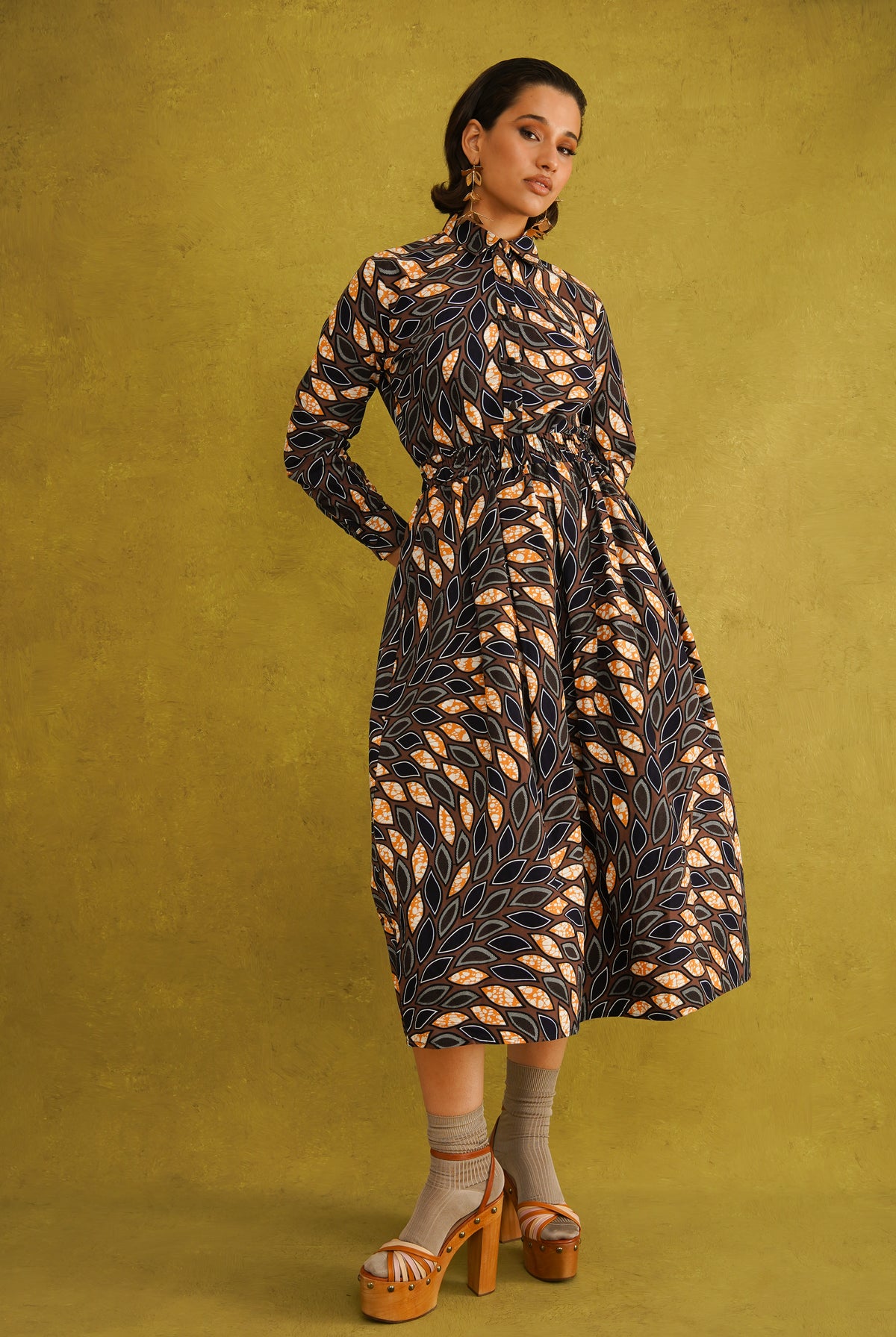 Eweko Cotton Midi Skirt, a tulip-shaped midi skirt in deep navy and orange leaf print Dutch wax cotton on a warm brown background