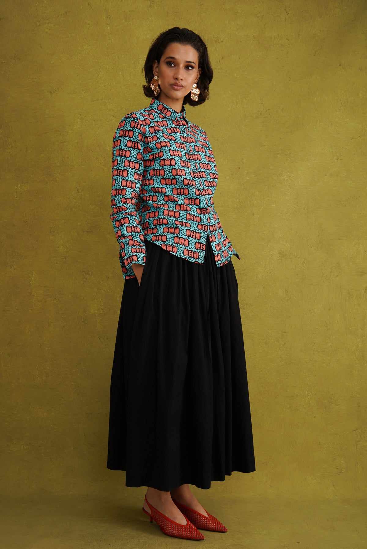Oge Adaze Shirt, a fitted shirt in Dutch wax cotton with coral-pink bows on a bright turquoise background