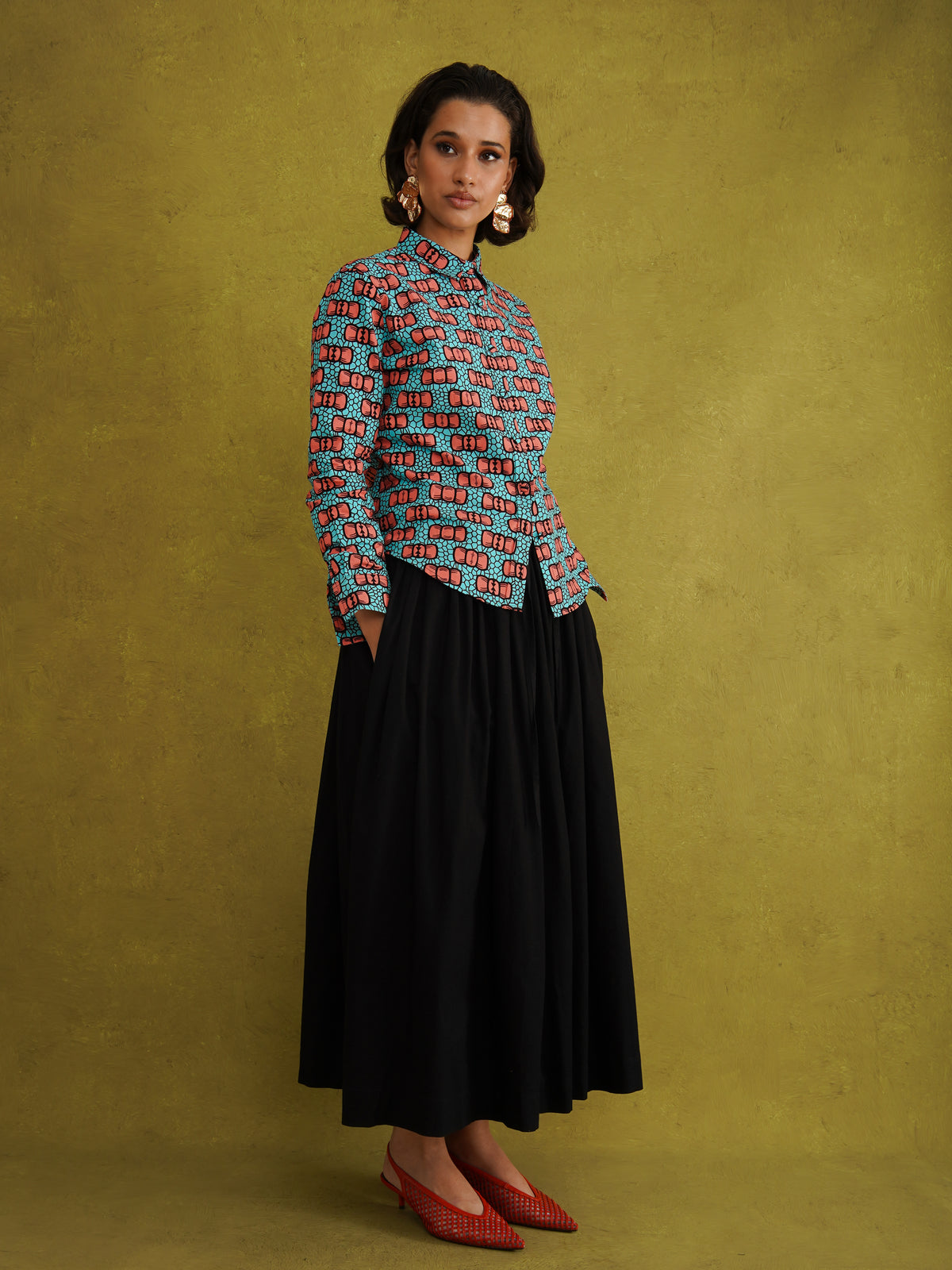 Oge Adaze Shirt, a fitted shirt in Dutch wax cotton with coral-pink bows on a bright turquoise background