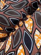 Eweko Cotton Midi Skirt, a tulip-shaped midi skirt in deep navy and orange leaf print Dutch wax cotton on a warm brown background
