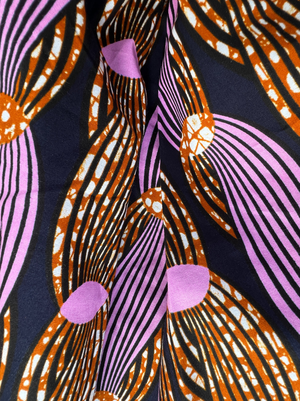 Irawo Cotton Midi Skirt, a tulip-shaped midi skirt in pink and orange shooting-star print Dutch wax cotton on a deep navy background