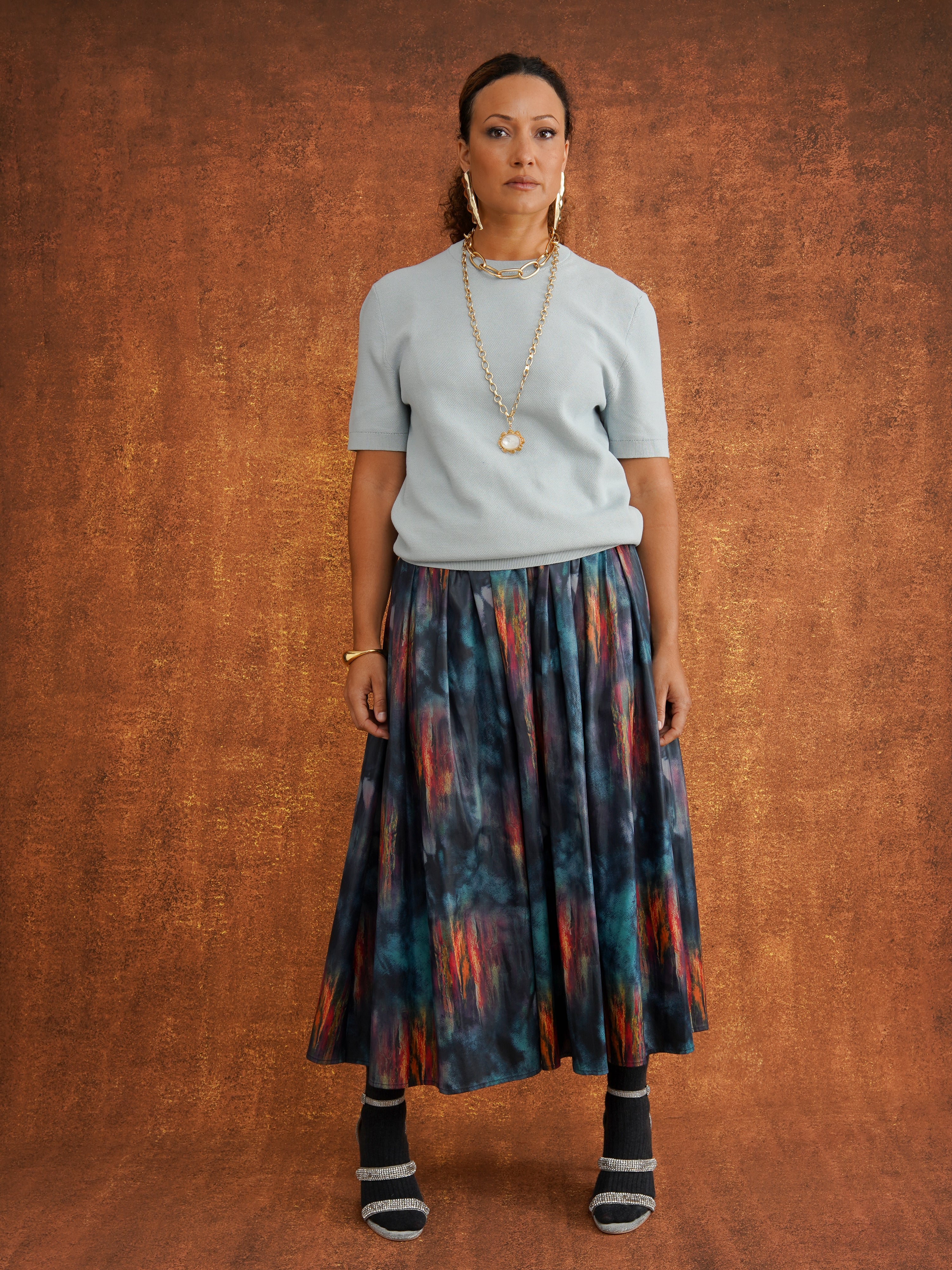 KemKem Abstract Midi Skirt in a bold abstract print of deep blues, purples, reds and oranges, with a patterned belt and metallic tips