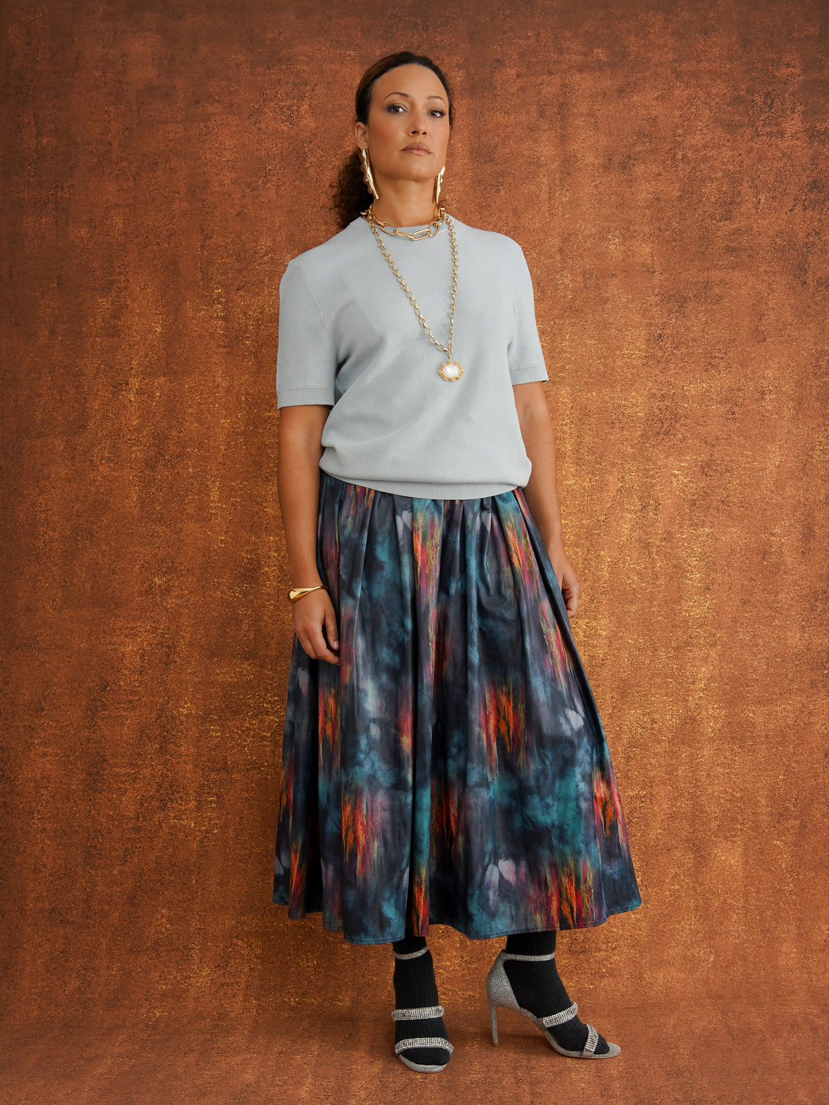 Angled front view of the KemKem Abstract Midi Skirt styled with a pale blue knit and dark socks