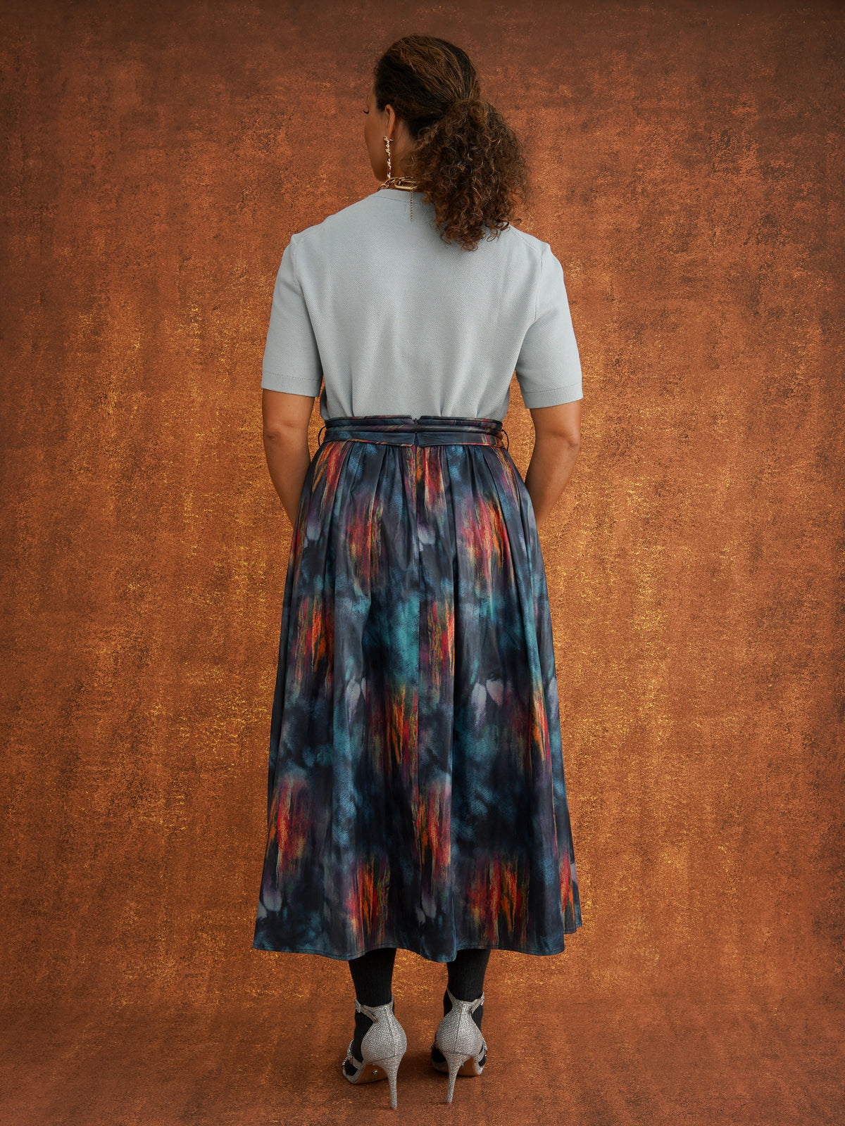 Back view of the KemKem Abstract Midi Skirt styled with a pale blue knit and dark socks
