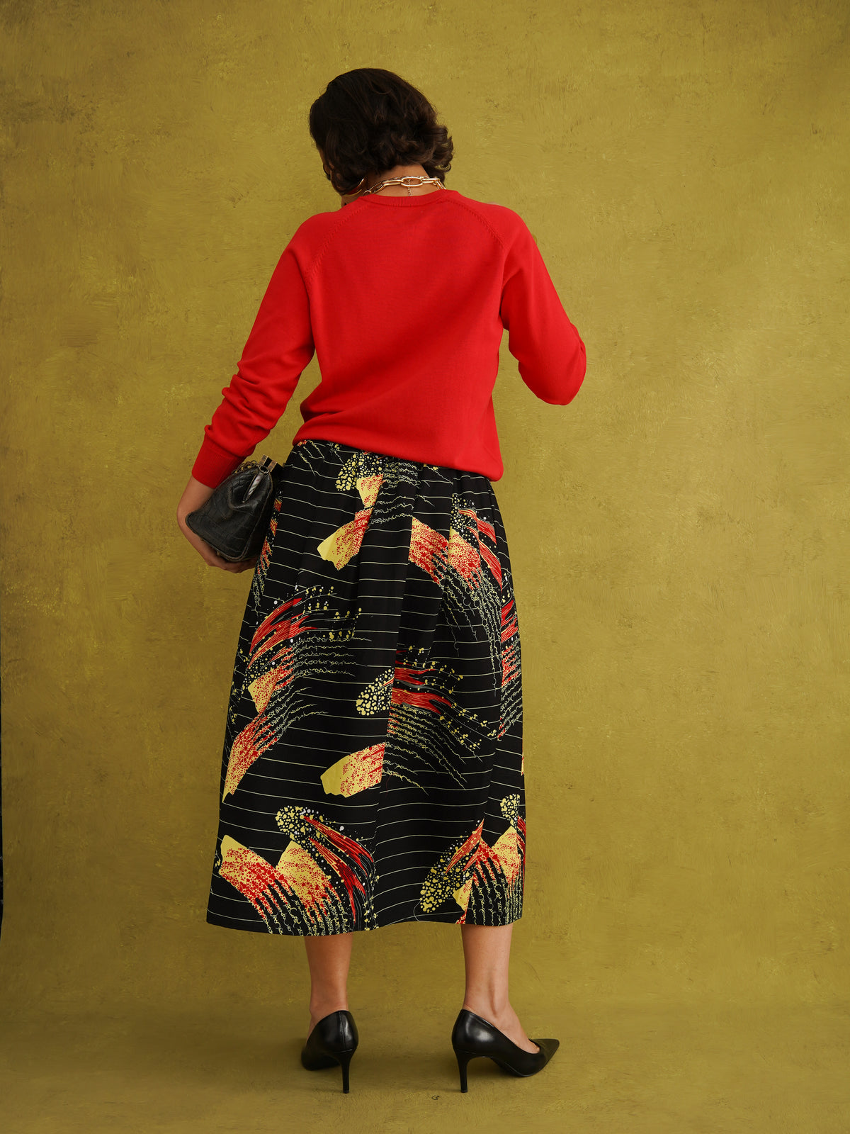 Ariya Cotton Midi Skirt, a tulip-shaped midi skirt in red and yellow Fireworks print Dutch wax cotton on a blue background