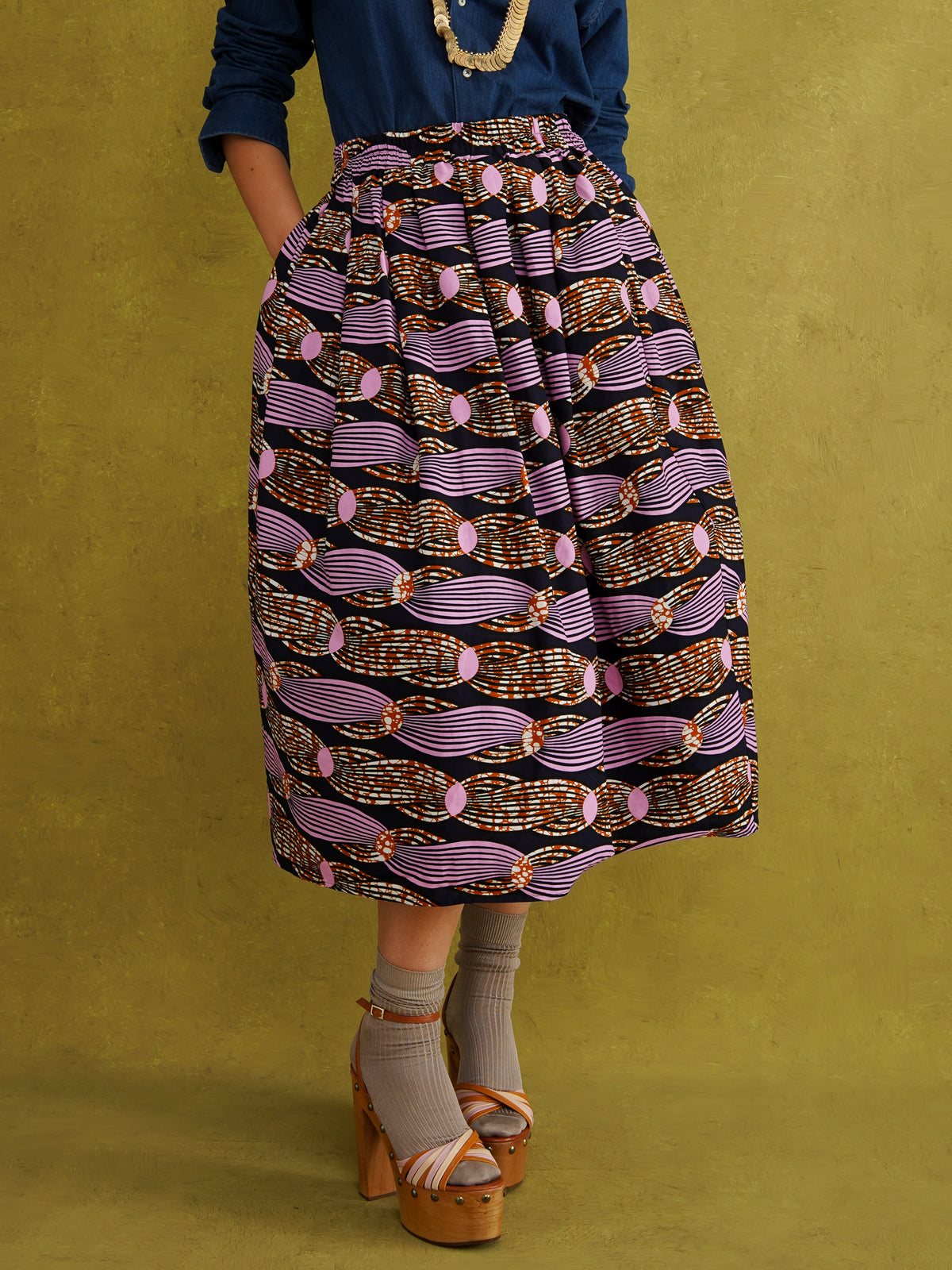Irawo Cotton Midi Skirt, a tulip-shaped midi skirt in pink and orange shooting-star print Dutch wax cotton on a deep navy background