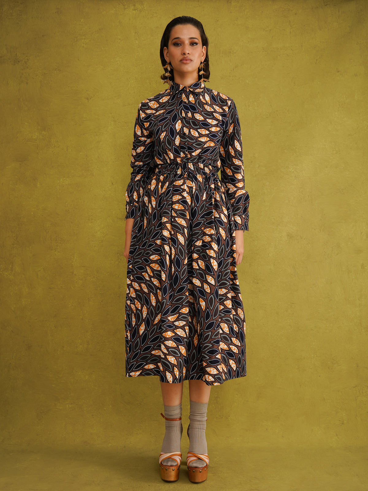 Eweko Adaze Shirt, a fitted shirt in deep navy and orange leaf print Dutch wax cotton on a warm brown background
