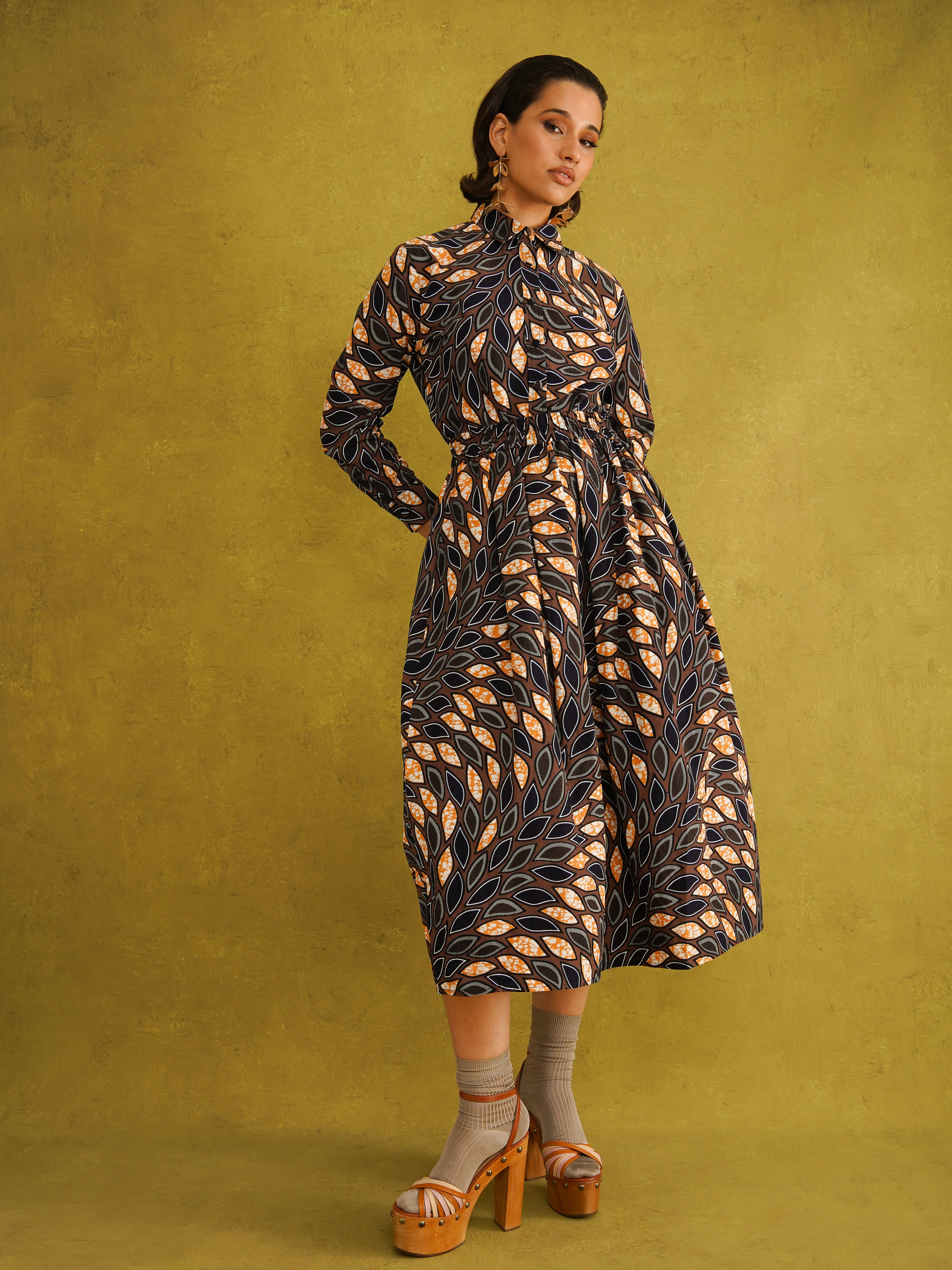 Eweko Cotton Midi Skirt, a tulip-shaped midi skirt in deep navy and orange leaf print Dutch wax cotton on a warm brown background