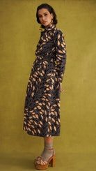 Eweko Cotton Midi Skirt, a tulip-shaped midi skirt in deep navy and orange leaf print Dutch wax cotton on a warm brown background