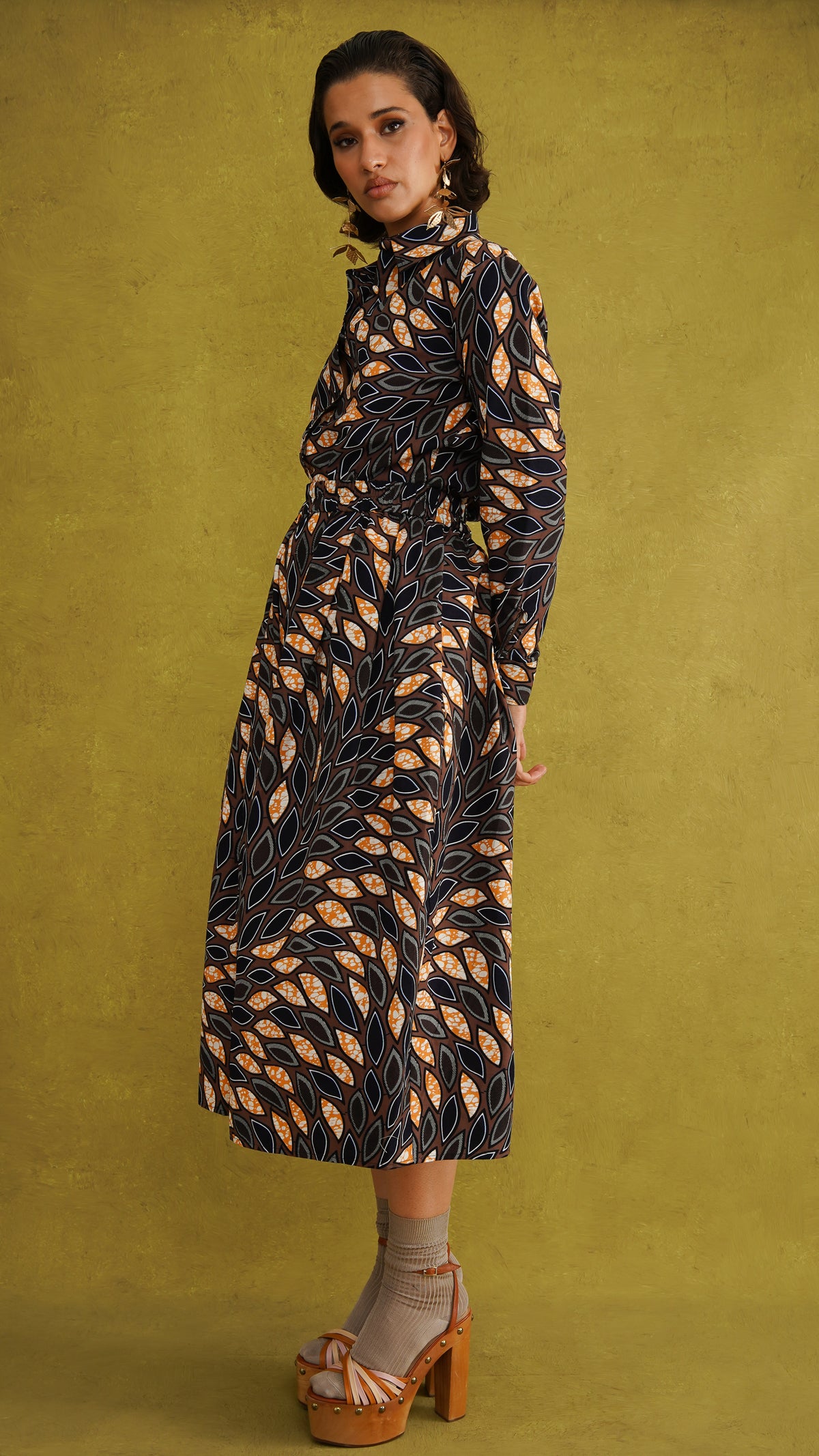 Eweko Cotton Midi Skirt, a tulip-shaped midi skirt in deep navy and orange leaf print Dutch wax cotton on a warm brown background