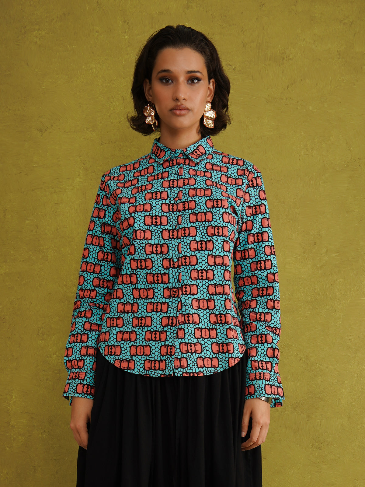 Oge Adaze Shirt, a fitted shirt in Dutch wax cotton with coral-pink bows on a bright turquoise background