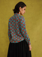 Oge Adaze Shirt, a fitted shirt in Dutch wax cotton with coral-pink bows on a bright turquoise background